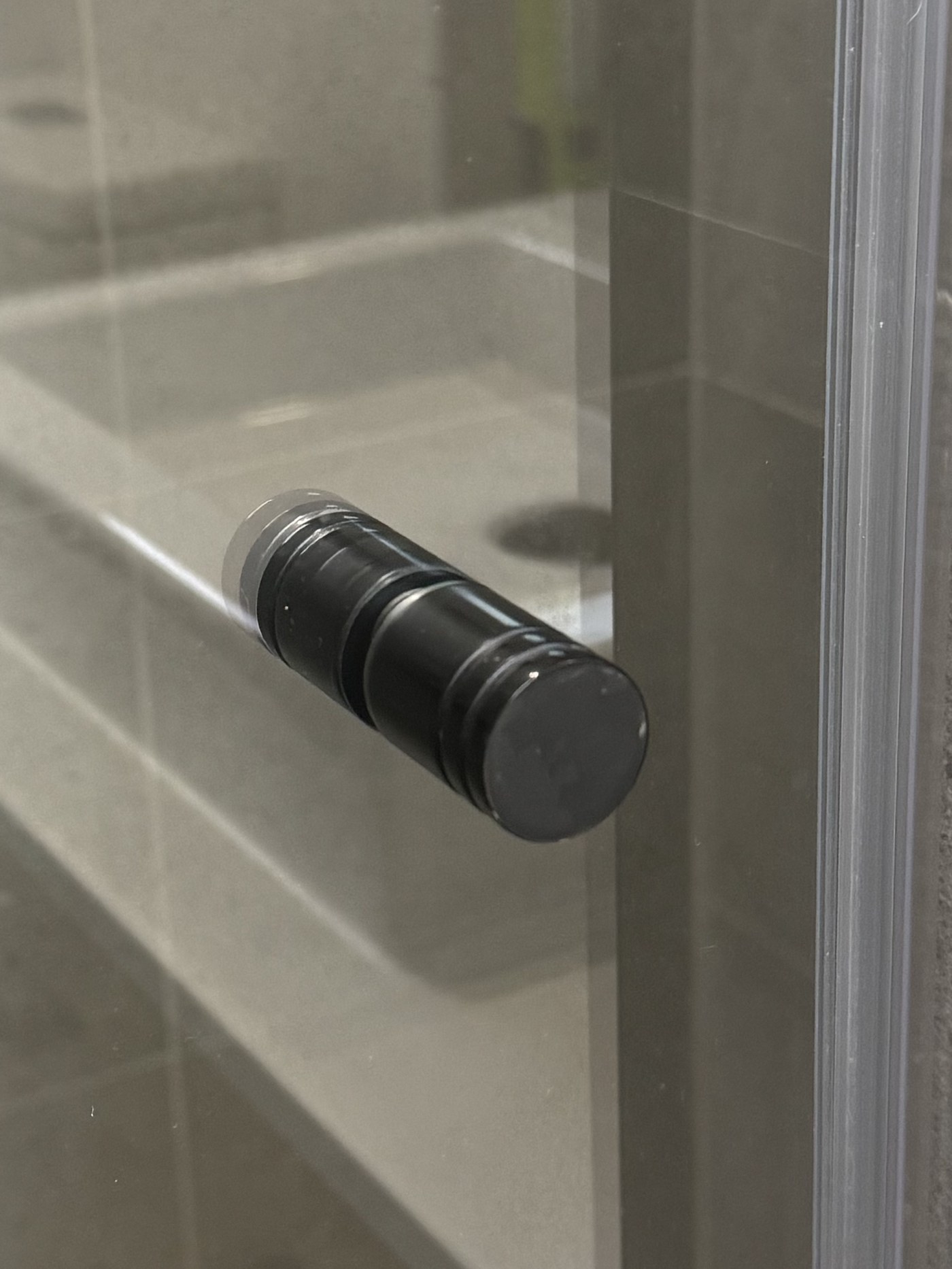 The same shower screen handle after OniClean coating, with the glass completely clear and mark-free