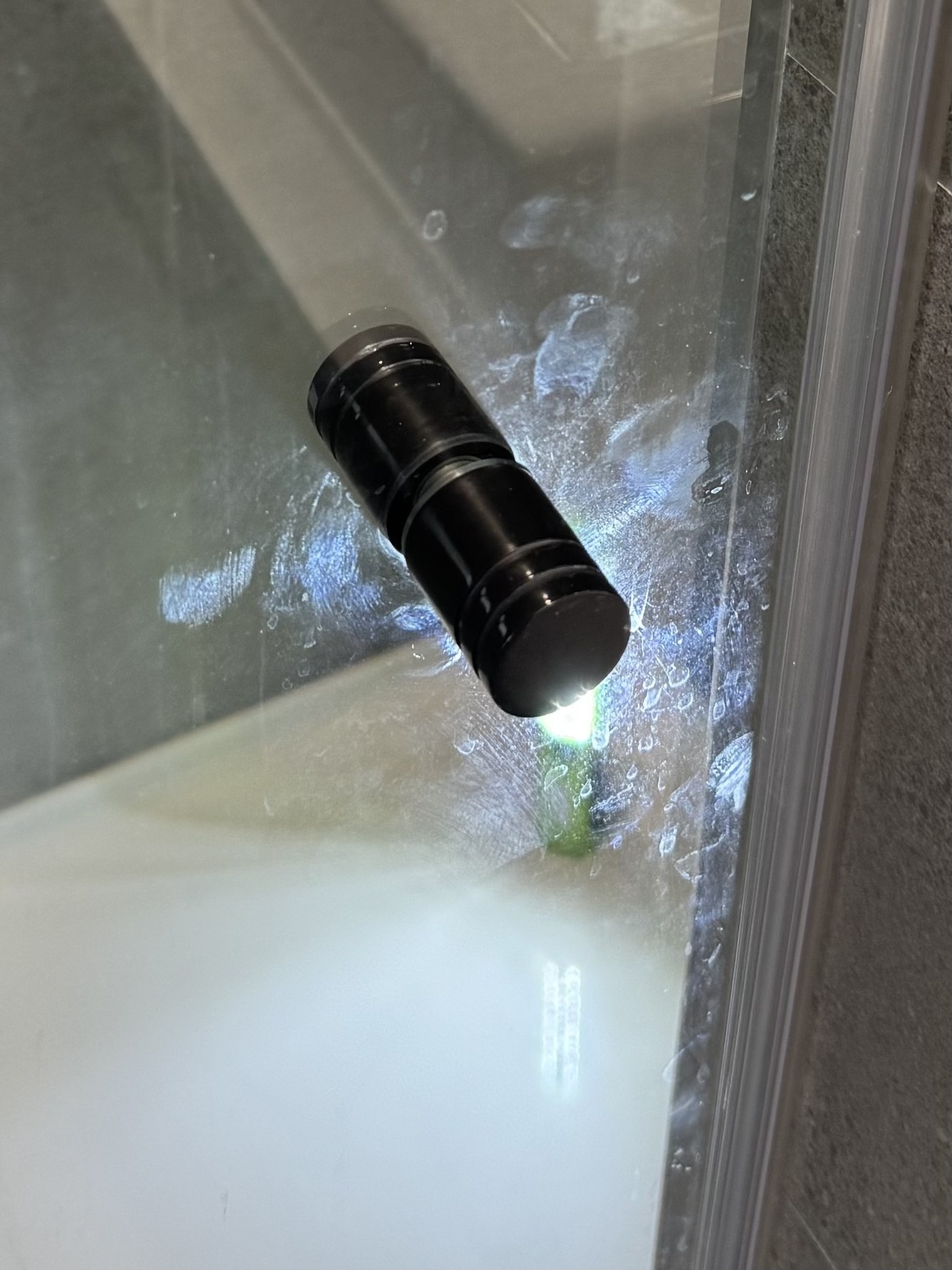 Shower screen handle before OniClean coating, with soap scum and fingerprint marks built up around the black handle