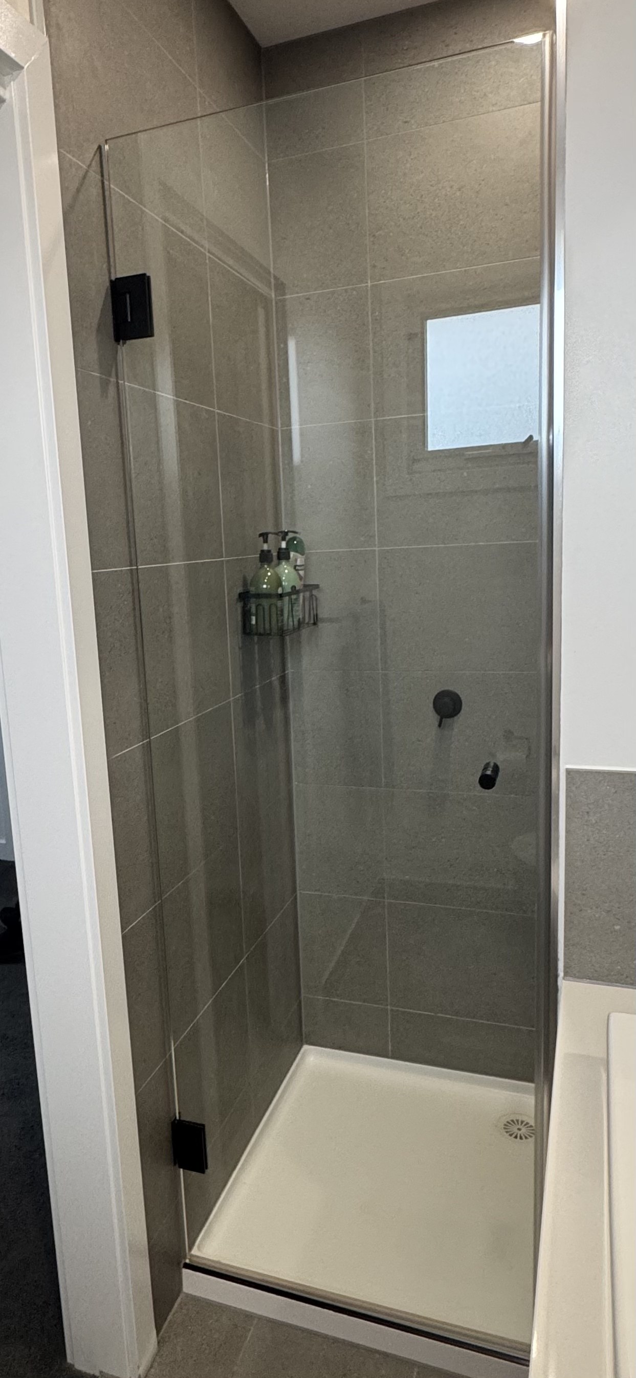 The same shower screen after OniClean coating, glass fully clear with no streaking or residue