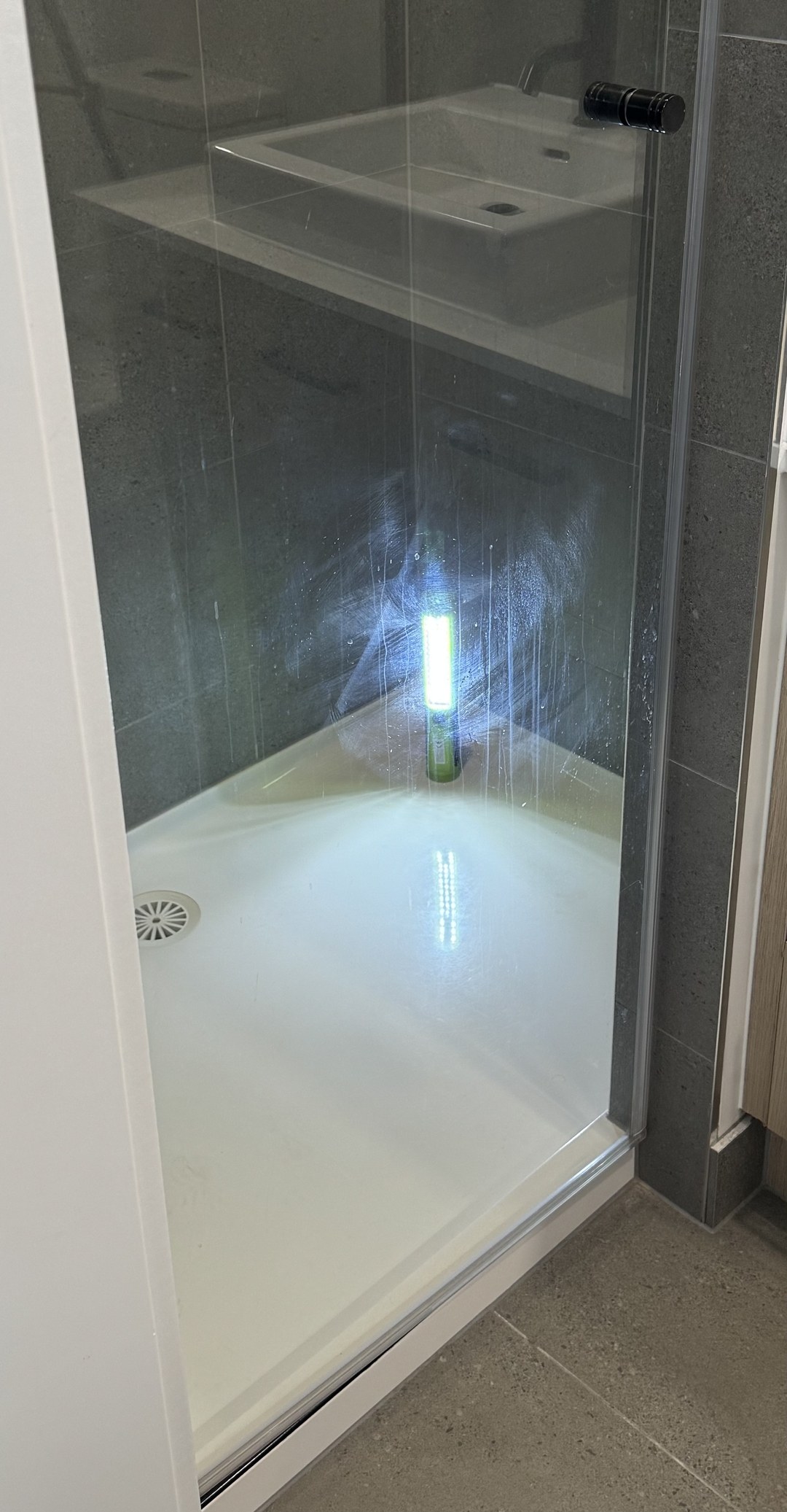 Shower screen before OniClean coating, with residue and streaking visible under a UV torch