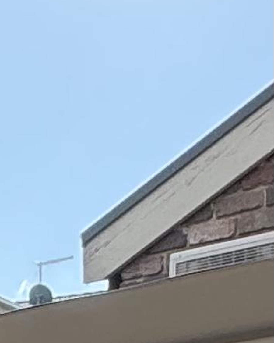 The same window roofline view after OniClean coating, glass crystal clear with sharp brick and vent detail visible
